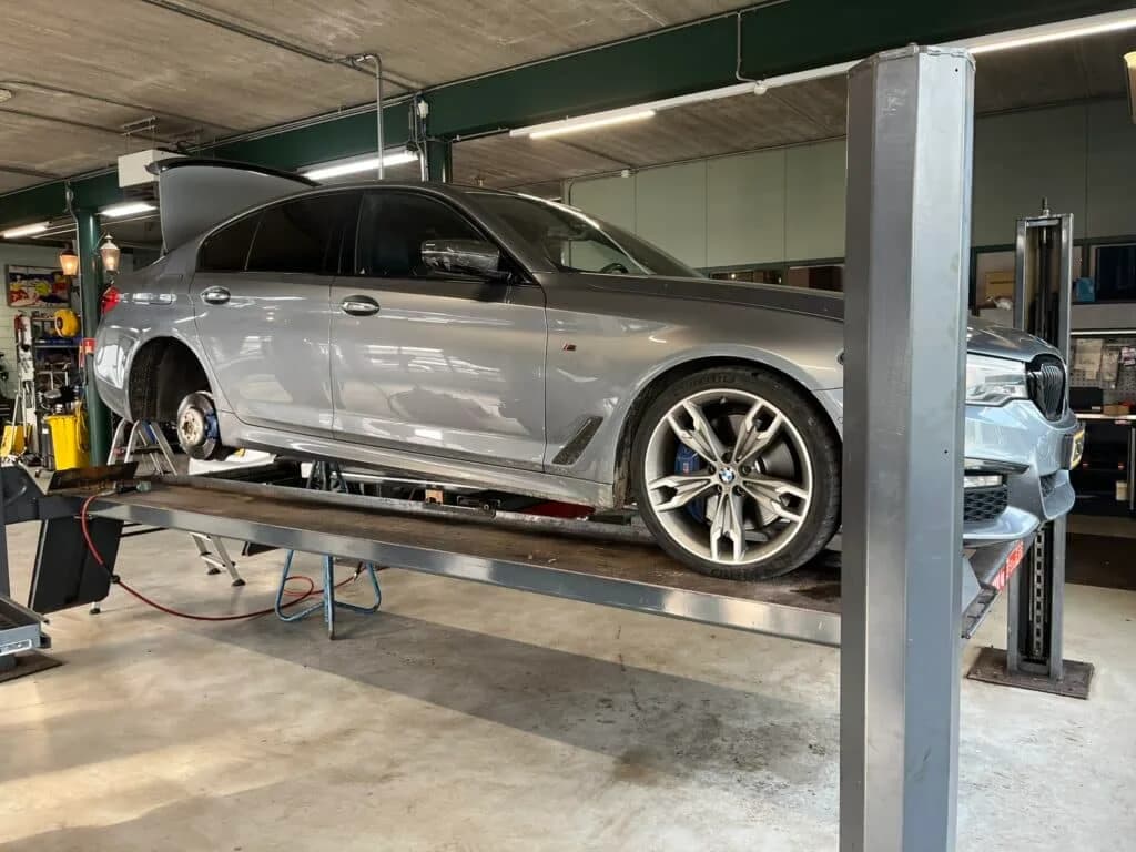 BMW op hefbrug voor APK-keuring en onderhoud — MTechniek Alkmaar Zilveren BMW op de platformhefbrug in de werkplaats van MTechniek voor APK-keuring of groot onderhoud.